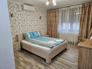 a bedroom with a bed with blue sheets and a window at Casa Giulia in Jimbolia