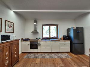 a kitchen with white cabinets and a black refrigerator at NEW Locanda da Raimondo - das Knarren der Zeit in Tarvisio