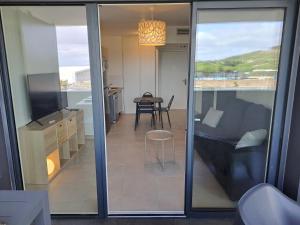 ein Wohnzimmer mit einem Sofa und einem Tisch mit einem Stuhl in der Unterkunft Iconic 343 , Superbe T2 climatisé, wifi, parking, terrasse 18m2 in Cap d'Agde