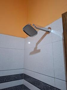 een badkamer met een douchekop aan de muur bij Casa Tangerina in Varkala