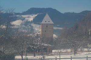 a tall building in the middle of a snow covered field at Bruggerhaus in Schöder