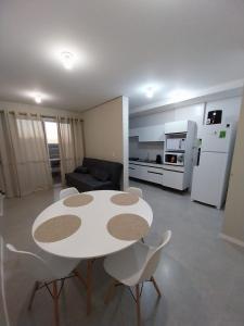 ein Wohnzimmer mit einem weißen Tisch und Stühlen in der Unterkunft Modern apartment steps from the beach with amenities in Arroio do Silva + 12 Fotos