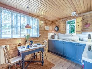 a kitchen with blue cabinets and a table with chairs at Hygge Cabin in Hexham +15 photos