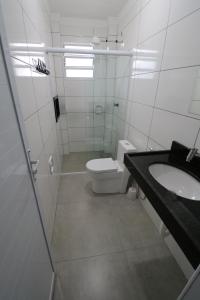 a white bathroom with a toilet and a sink at Recanto Ubaduba in Ubatuba +5 photos