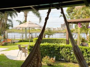 托雷斯Pousada Brisas do Rio的门廊配有吊床和桌椅