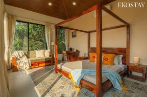 a bedroom with a canopy bed and a living room at EKOSTAY - Brick Wood in Karjat +22 photos