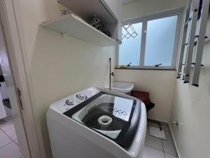 eine Waschmaschine in einem kleinen Bad mit Fenster in der Unterkunft Ótima Localização!!! Apartamento De Frente No Centro De Capão Da Canoa in Capão da Canoa + 97 Fotos