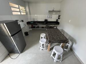 a kitchen with a table with stools and a refrigerator at Recanto Ubaduba in Ubatuba