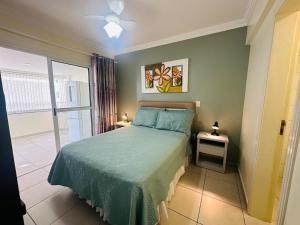 ein Schlafzimmer mit einem Bett mit einer grünen Tagesdecke und einem Fenster in der Unterkunft Ótima Localização!!! Apartamento De Frente No Centro De Capão Da Canoa in Capão da Canoa