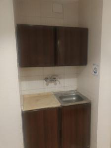 Una cocina con fregadero y armarios de madera. en Zwar Alharam Makkah Hotel, en La Meca