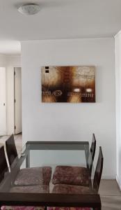 a glass table with two chairs and a painting on a wall at A pasos de Ruta Cinco y Universidad in Talca