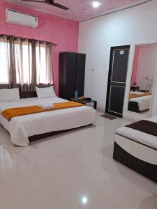1 Schlafzimmer mit 2 Betten und einer rosa Wand in der Unterkunft Vrindavan Hotel and Restaurant in Malavli + 32 Fotos