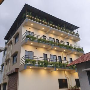 ein weißes Gebäude mit Pflanzen auf den Balkonen in der Unterkunft Vrindavan Hotel and Restaurant in Malavli