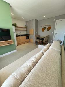 a living room with a couch and a kitchen at Apto Home & Club em Capão da Canoa in Capão da Canoa