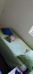 a small bed with green sheets and blue pillows at A pasos de Ruta Cinco y Universidad in Talca