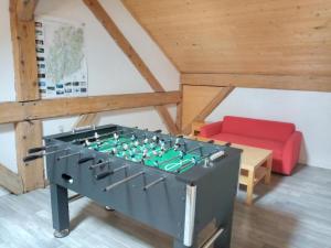 een tafelvoetbalspel in een kamer met een rode bank bij L'Escapade gîte proche des Cascades du Hérisson in La Celle-sous-Gouzon