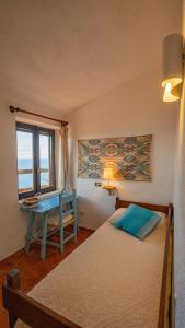 a bedroom with a bed and a desk and a window at Casa Cielo Mare in Costa Paradiso