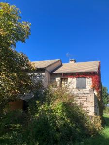 an old stone house with red ivy on it at Gîte Les Aires de la Carline in Mas Saint-Chély