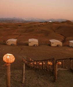 een groep gebouwen in een veld met bergen op de achtergrond bij Agafay Private evening camel ride sunset dinner show private experience in Marrakesh +11 foto's