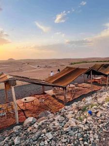 een groep mensen die onder een afdak in de woestijn staan bij Agafay Private evening camel ride sunset dinner show private experience in Marrakesh