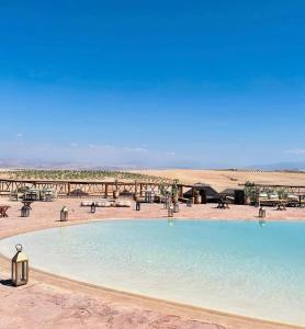 een groot zwembad midden in de woestijn bij Agafay Private evening camel ride sunset dinner show private experience in Marrakesh