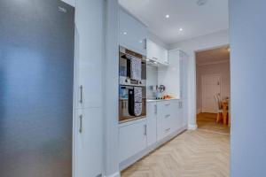 a white kitchen with white cabinets and a table at Manor Castle View 3BR House Free Parking & Garden in Victoria