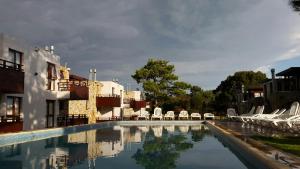 ein Pool mit weißen Stühlen und ein Gebäude in der Unterkunft Cabañas Arenas Blandas in Villa Gesell