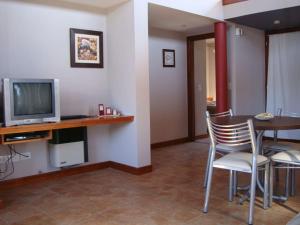 sala de estar con mesa con sillas y TV en Cabañas Arenas Blandas, en Villa Gesell