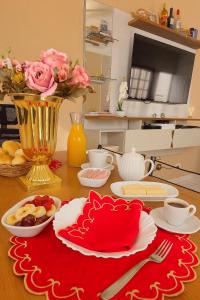 une table avec une assiette de nourriture et un vase avec des fleurs dans l'établissement Casa Lopes temporada Ubatuba, à Ubatuba