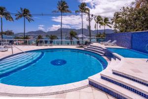Una gran piscina con palmeras en un complejo turístico. en Hotel Ilhabela, en Ilhabela