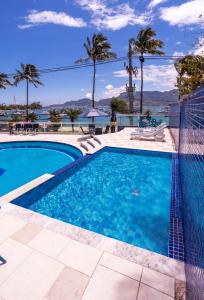 a swimming pool with a view of the water and palm trees at Hotel Ilhabela in Ilhabela