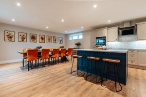 a kitchen with a blue island and orange bar stools at The Stables - Newly Renovated 4 bed house in Catworth