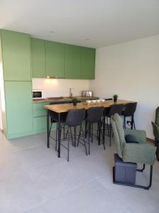 a kitchen with green cabinets and a table and chairs at Casa Terra das Vinhas in Esposende