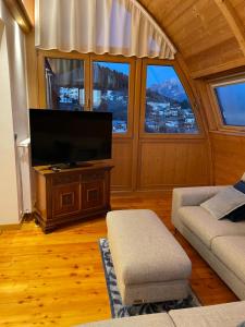 een woonkamer met een flatscreen-tv en een bank bij Luna Rossa Dolomiti in Domegge di Cadore