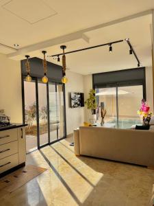a living room with a couch and a large window at Villa 2 Évasion Urbaine, 3 Chambres, à 20 min de Rabat in Sidi Yahia az Zaʼer