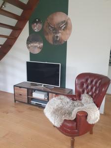 a living room with a leather chair and a television at Boshuis 40 in Epe