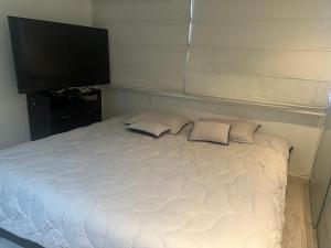 een wit bed met 2 kussens en een flatscreen-tv bij Habitación Deluxe in Bogota
