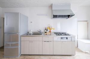 a white kitchen with a sink and a refrigerator at Matsumoto Inn in Matsumoto