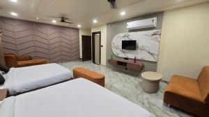 um quarto de hotel com duas camas e uma TV de tela plana em Hotel Pinaki em Ajmer