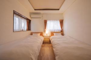 twee bedden in een kleine kamer met een raam bij Matsumoto Inn in Matsumoto