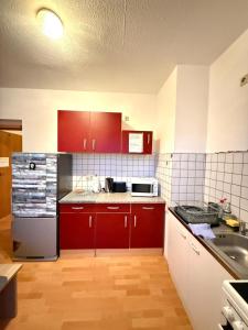 een keuken met rode kasten en een roestvrijstalen koelkast bij Geräumige Wohnung Nähe HBF in Eisenach