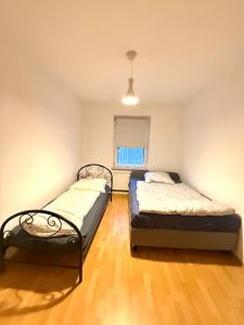 twee bedden in een kamer met houten vloeren en een raam bij Geräumige Wohnung Nähe HBF in Eisenach