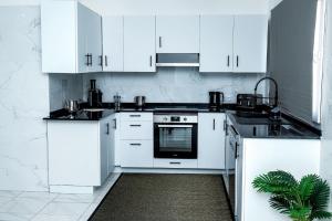a white kitchen with white cabinets and a sink at Saton 24H Guest House in São Tomé