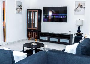 a living room with a blue couch and a tv at Saton 24H Guest House in São Tomé