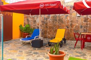a patio with colorful chairs and an umbrella at Saton 24H Guest House in São Tomé