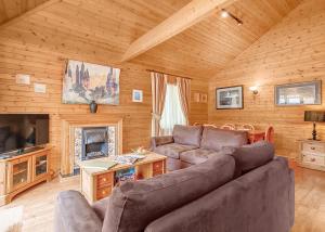 een woonkamer met een bank en een televisie in een hut bij Tilford Woods Lodge Retreat in Farnham