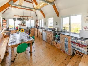 een keuken met houten vloeren en een tafel met groene stoelen bij Lower Hendra Cottage in Port Isaac