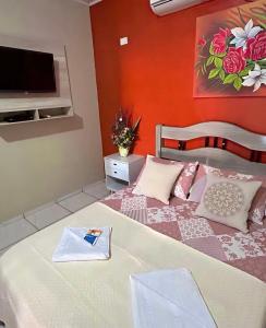 una camera da letto con un letto e una TV a parete di Pousada Novo Amanhecer a Itarema