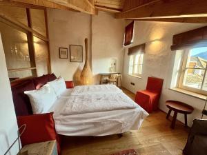 een slaapkamer met een wit bed en rode stoelen bij Ansitz Jenner in Appiano sulla Strada del Vino
