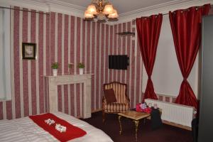 um quarto com uma cama, uma cadeira e cortinas vermelhas em Hotel Het Gasthof em Herent